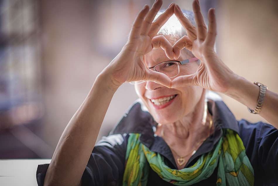 senior woman with glasses making heart shape in front of face