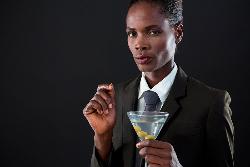 black androgynous person in suit drinking a martini