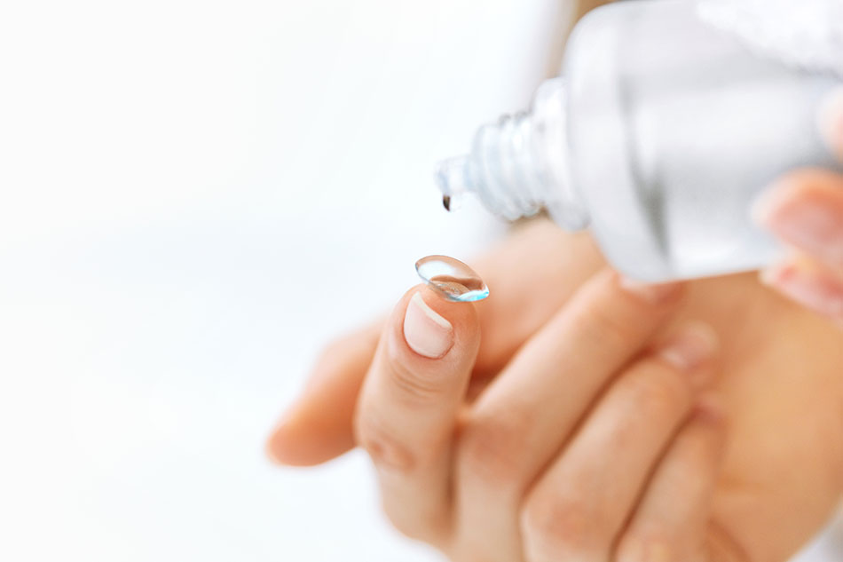 woman cleaning contact lens on fingertip
