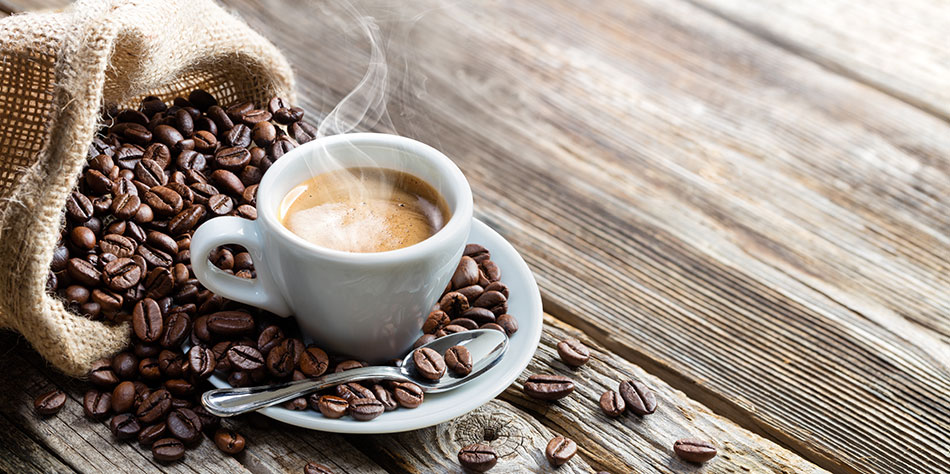 Cup of coffee with beans on wooden table