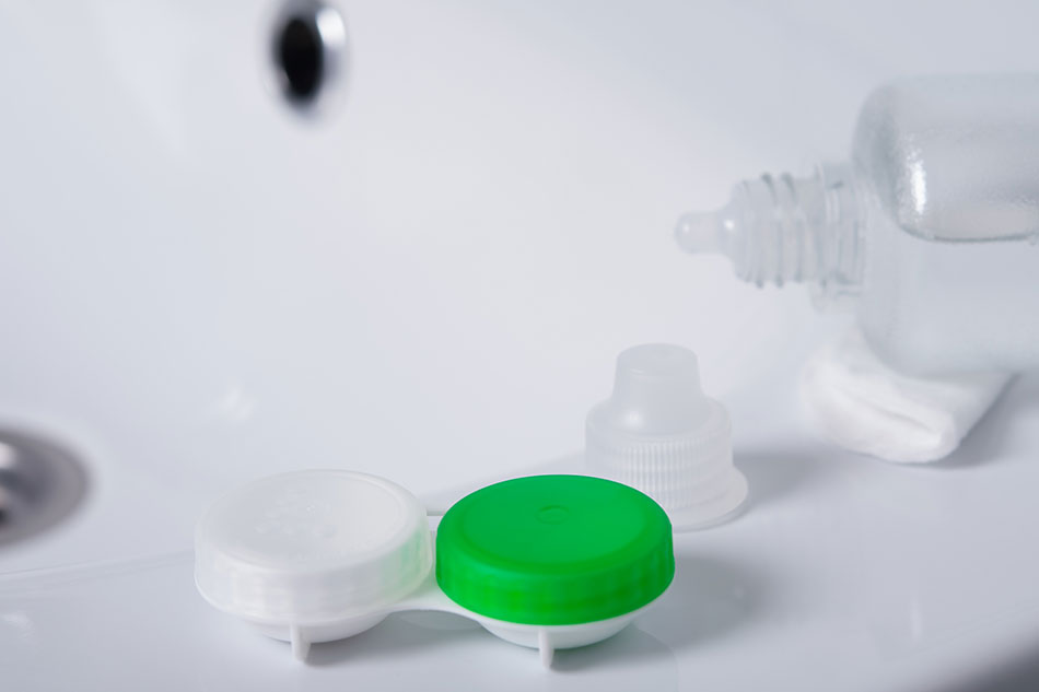 Contact lens case with open solution bottle on side of bathroom sink