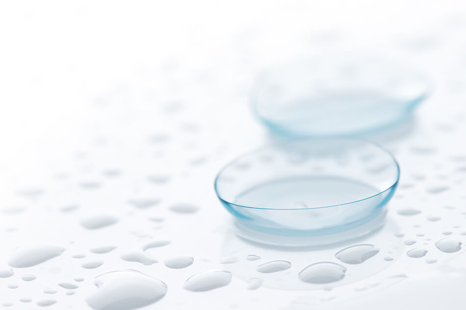 two contact lenses and water droplets on white table top