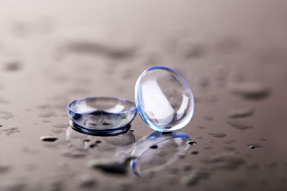 Contact lenses on reflective surface with water drops