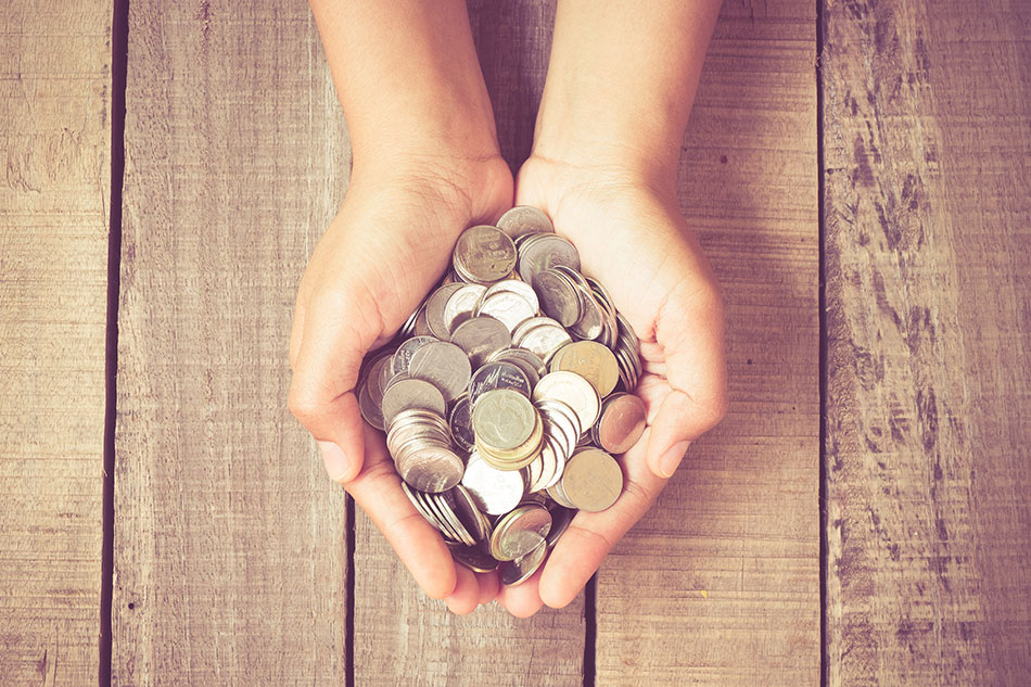 cupped hands filled with coins on wooden table