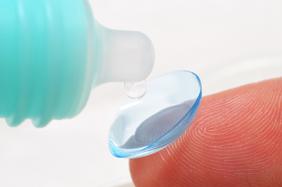 extreme close up of putting lens solution on contact lens on fingertip