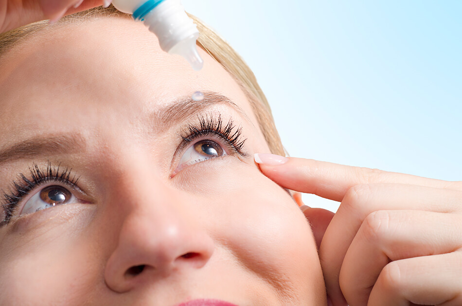 closeup of young woman applying eye drops