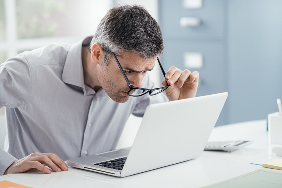 man squinting to see computer screen