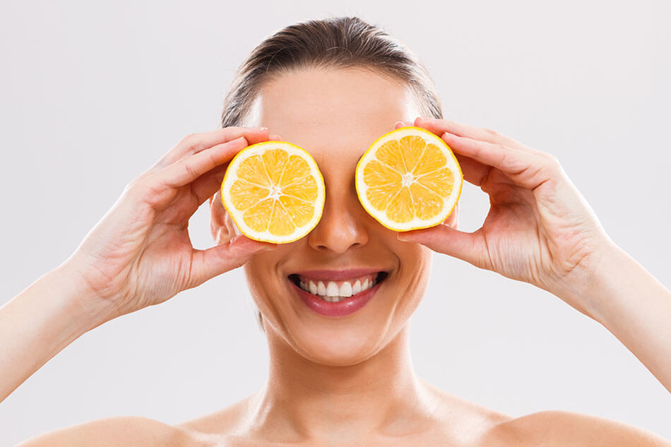 Woman holding lemon slices up to her eyes