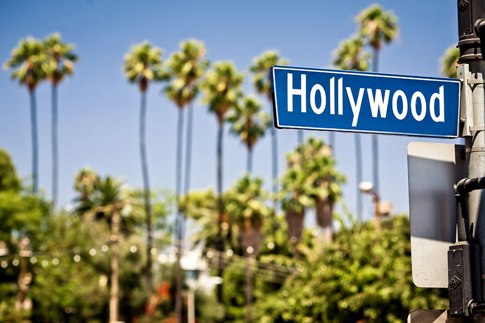 Hollywood street sign with palm trees and blue sky