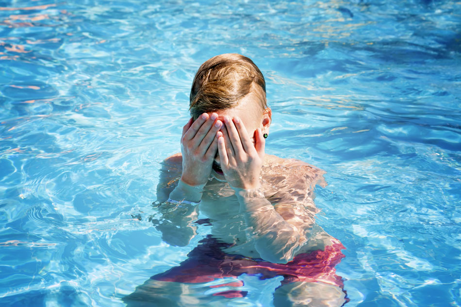 Male teenager swimming with contacts and having eye pain