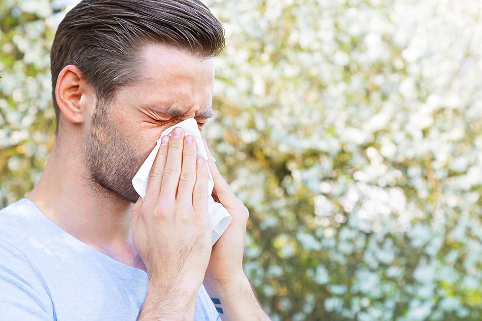 Man with contact lens allergy sneezing into napkin