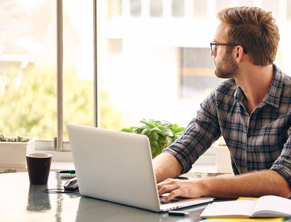 man working on computer looking out window