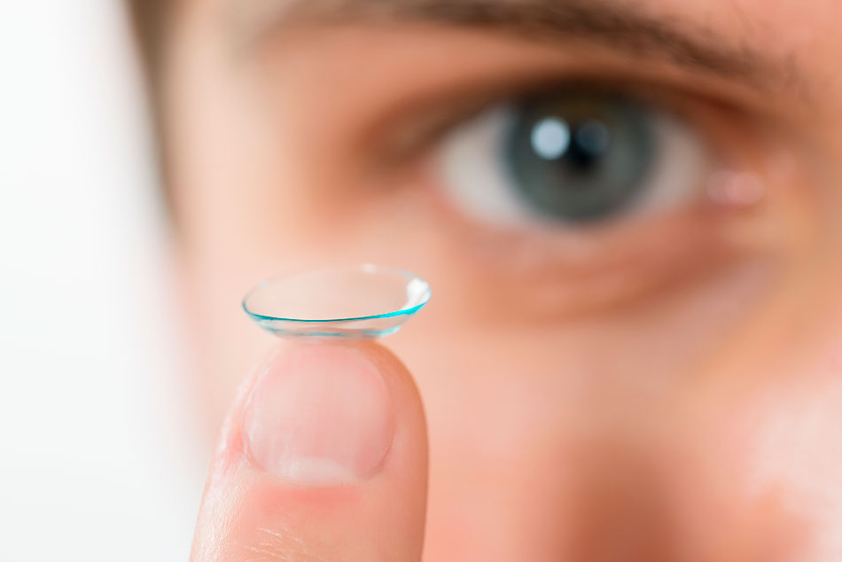 man showing contact lens on finger
