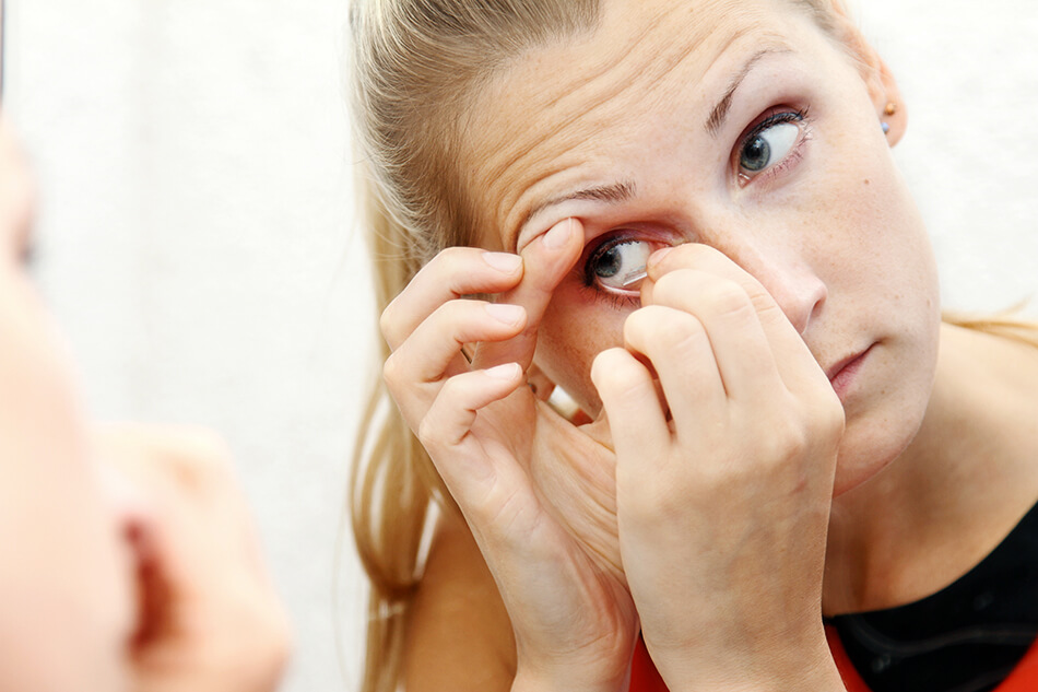 woman removing a contact lens