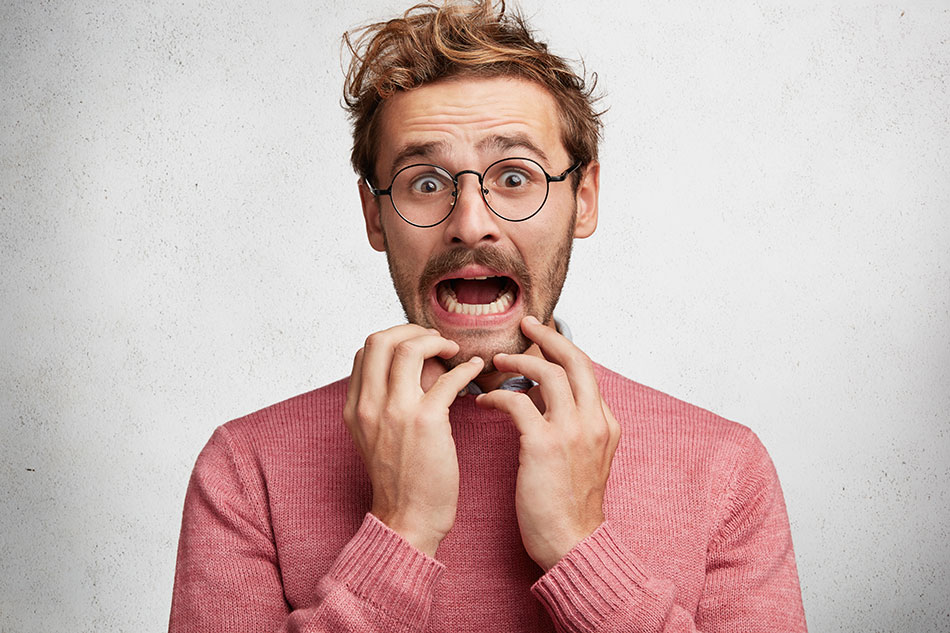 scared man in pink sweater with eyeglasses