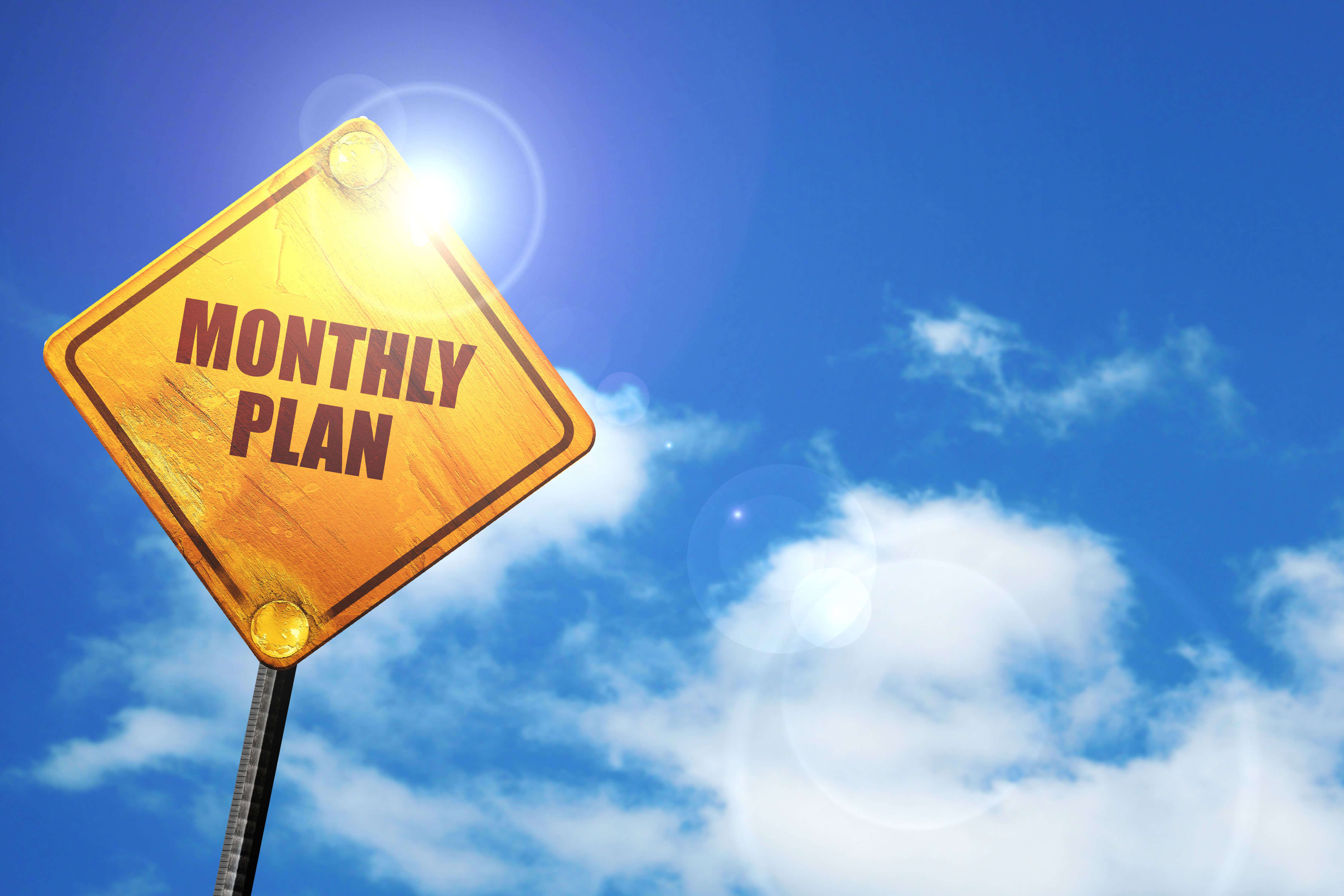 Street sign saying monthly plan against blue sky