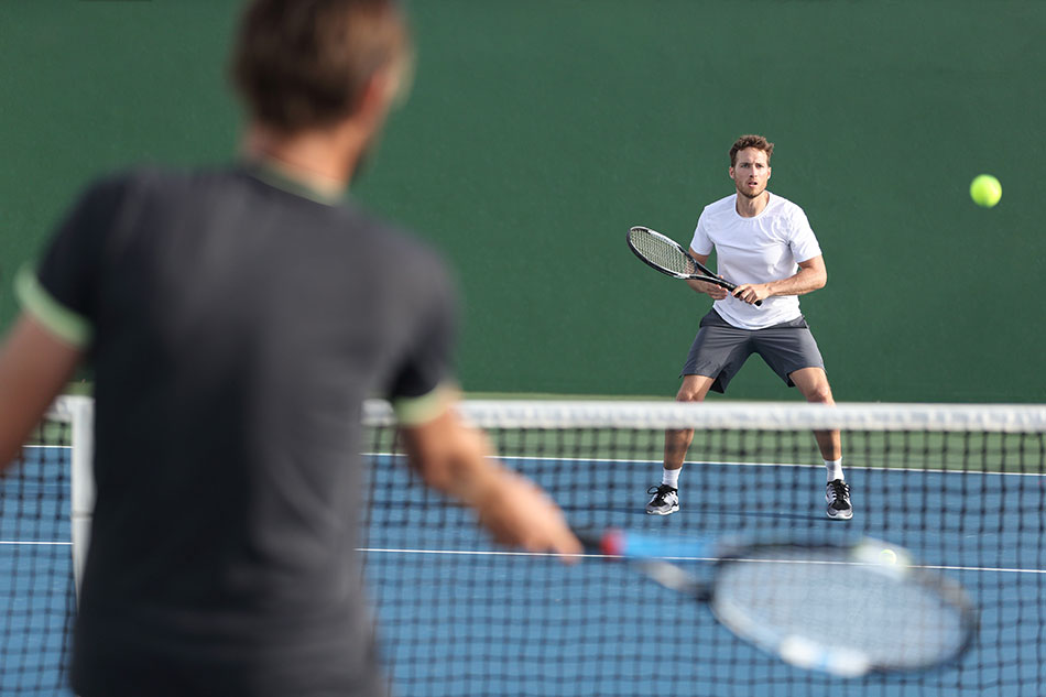 man waiting to hit tennis ball in mid-air