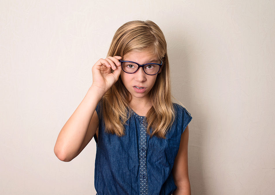 Unhappy young girl adjusting glasses