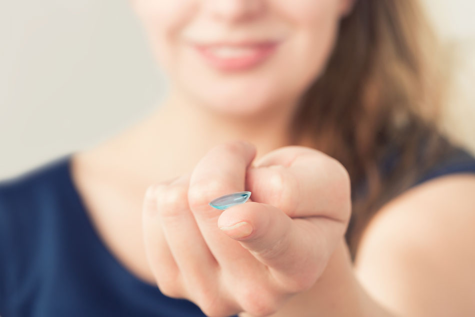 Woman with contact lens on fingertip