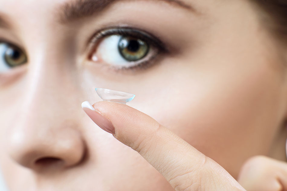 woman with contact lens on fingertip