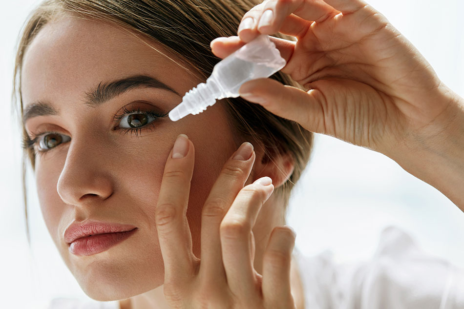 woman putting eye drops in left eye