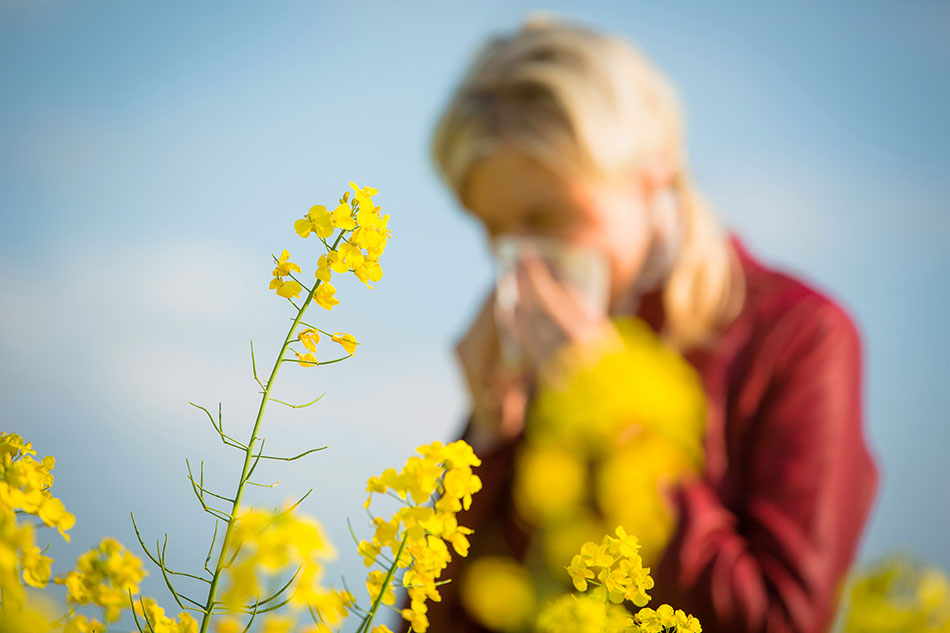 Woman blowing nose in field of flowers