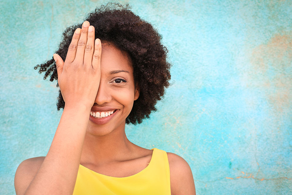 woman with one hand over her eye, blue background