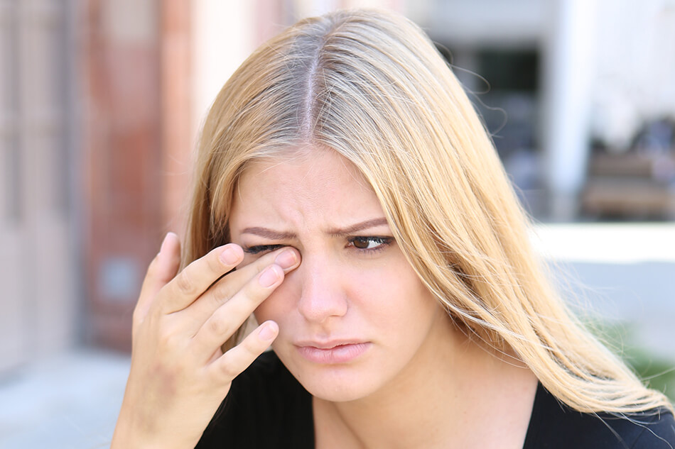 woman with hand to face due to contact lens irritation