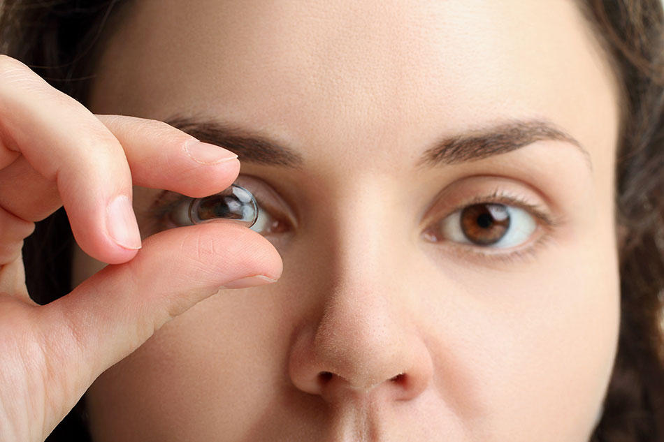 Woman looking through contact lens held up to her eye