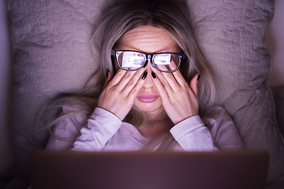woman in bed experiencing computer eye strain