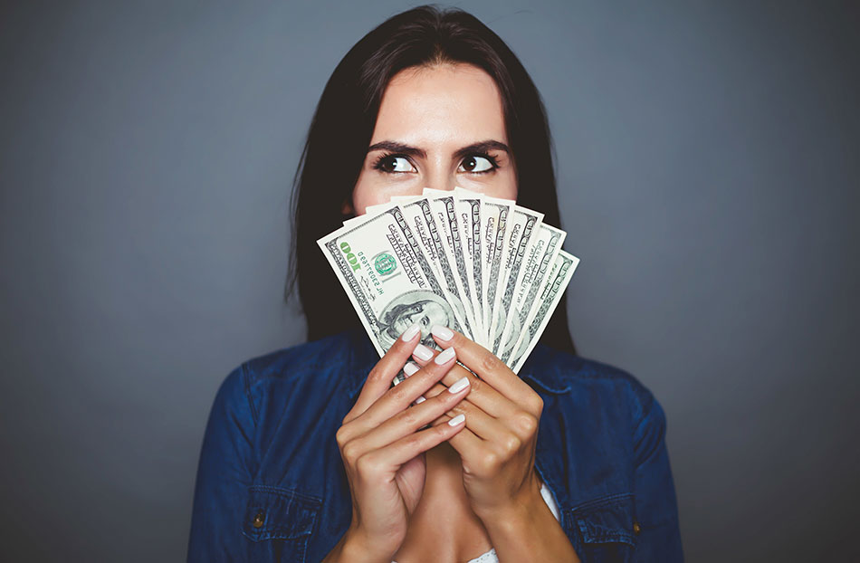 woman holding money in front of face