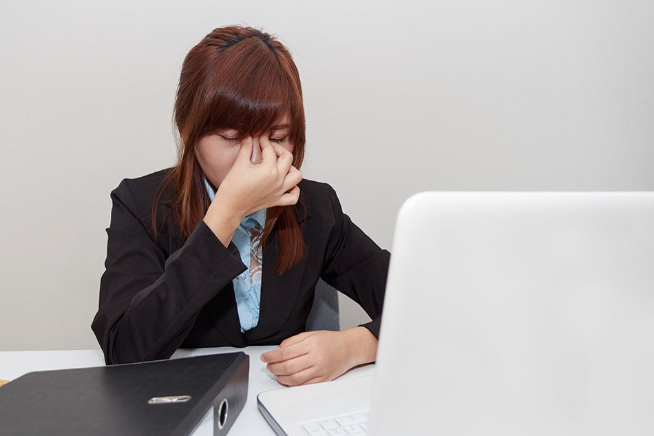 woman at computer rubbing her eyes due to eye strain