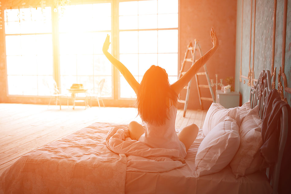 woman stretching on the bed in the morning sun