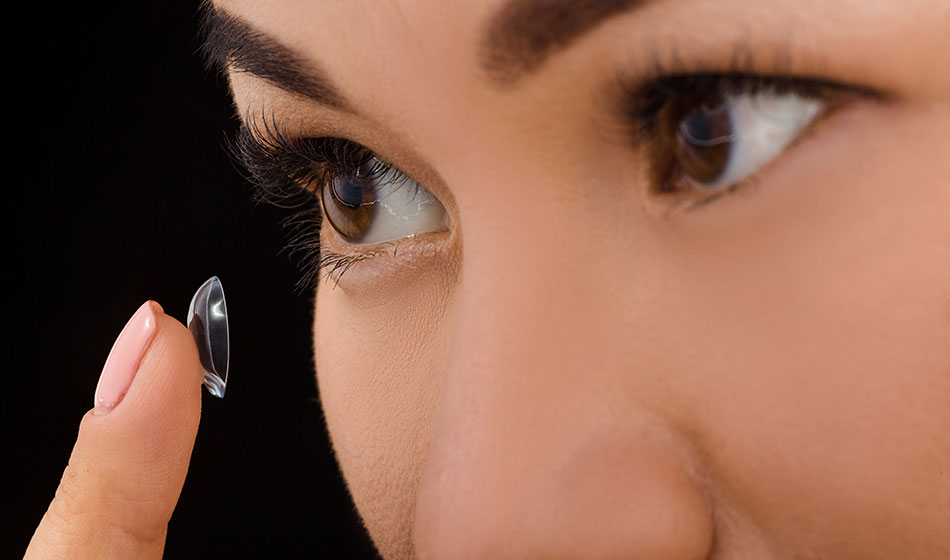 woman inserting contact lens into eye