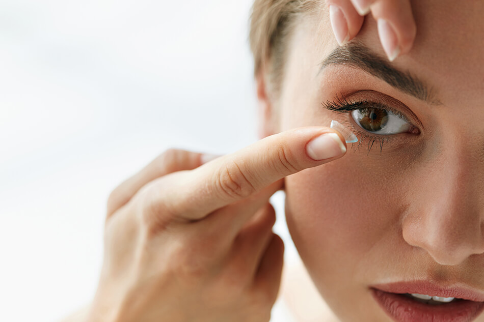 woman inserting contact lens into eye