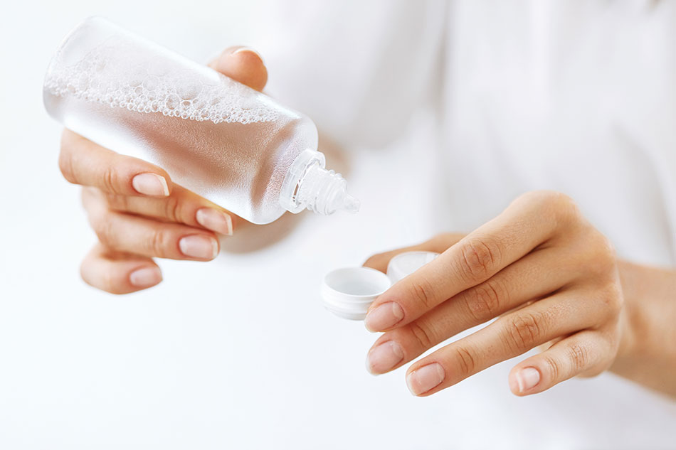 Woman’s hands putting contact solution into lens case