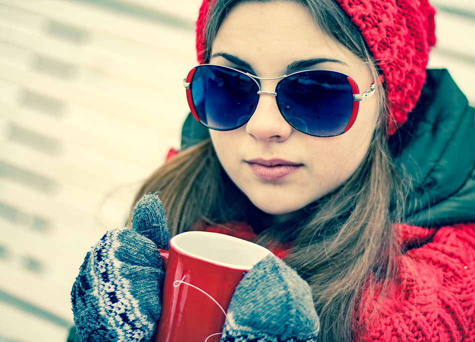 young woman drinking tea and wearing sunglasses in winter