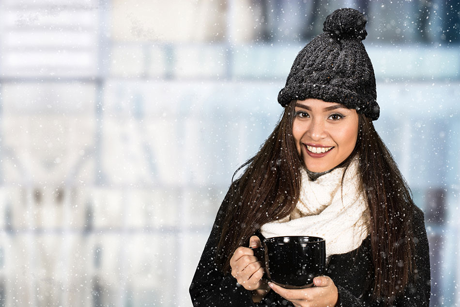 young woman outside in the snow holding a hot drink in a mug